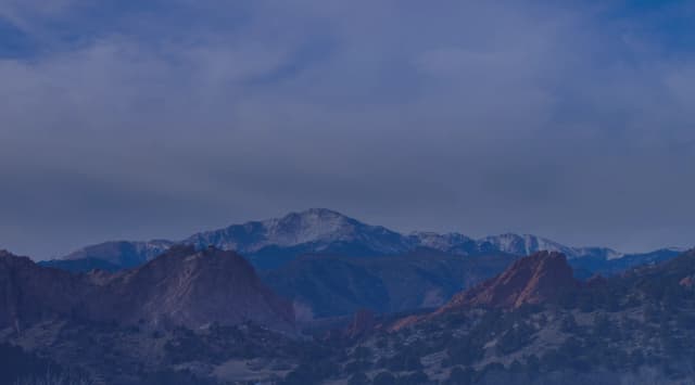 Red sandstone formations at Garden of the Gods with snow-capped Pikes Peak behind them near Colorado Springs