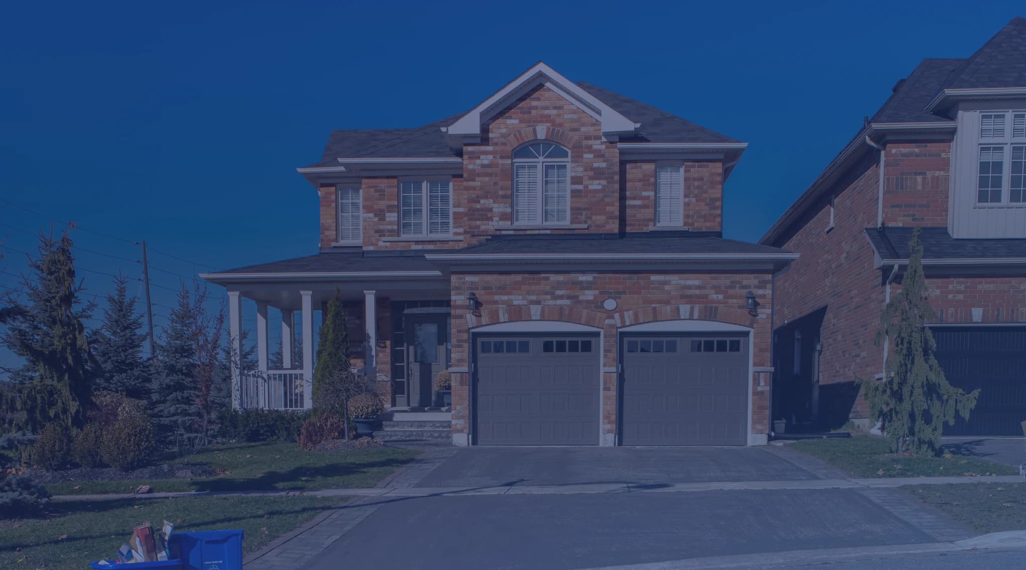 A two-story brick suburban home with a covered front porch and a two-car garage
