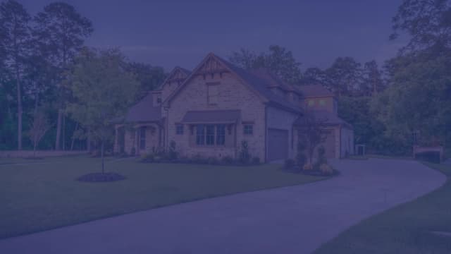 A two-story brick family home in Florida with a curved driveway and landscaped front yard at dusk