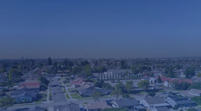 An aerial view of a suburban neighborhood with houses and trees under a clear sky