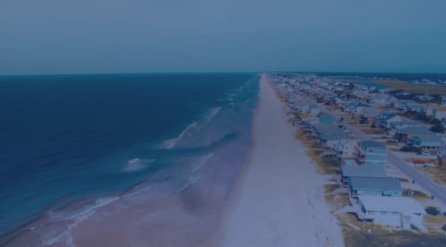 Aerial view of a North Carolina barrier island beach with waves rolling in beside a row of beach houses
