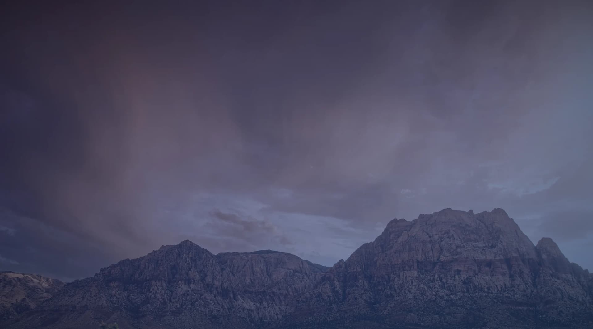Red rock mountains and desert scrub under a dramatic sky near Las Vegas, Nevada.