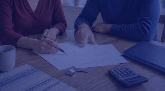 Homeowners reviewing mortgage paperwork, a calculator, and house keys
