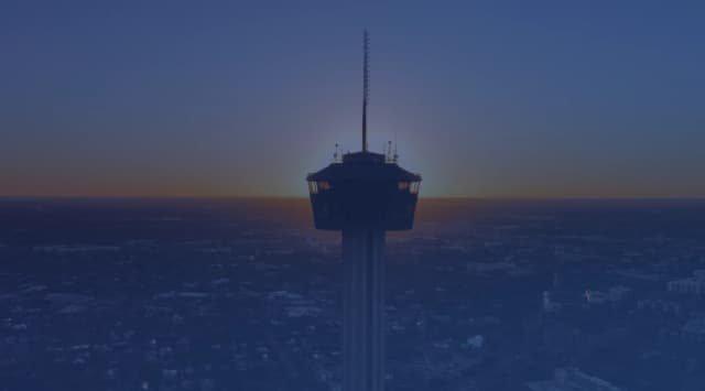 Silhouette of the Tower of the Americas against a sunset over San Antonio, Texas