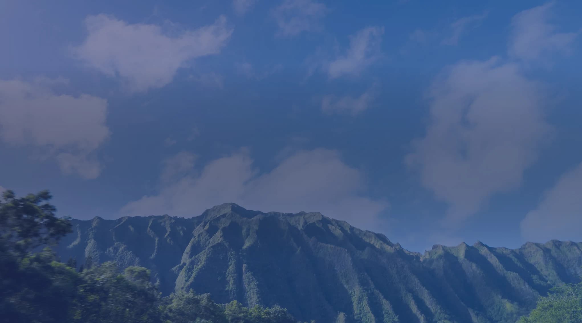 Rows of two-story military family homes on Oahu with the green Waianae mountain range rising behind them