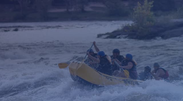 A whitewater raft crew in helmets paddles through rapids on the Chattahoochee River in Columbus, Georgia.