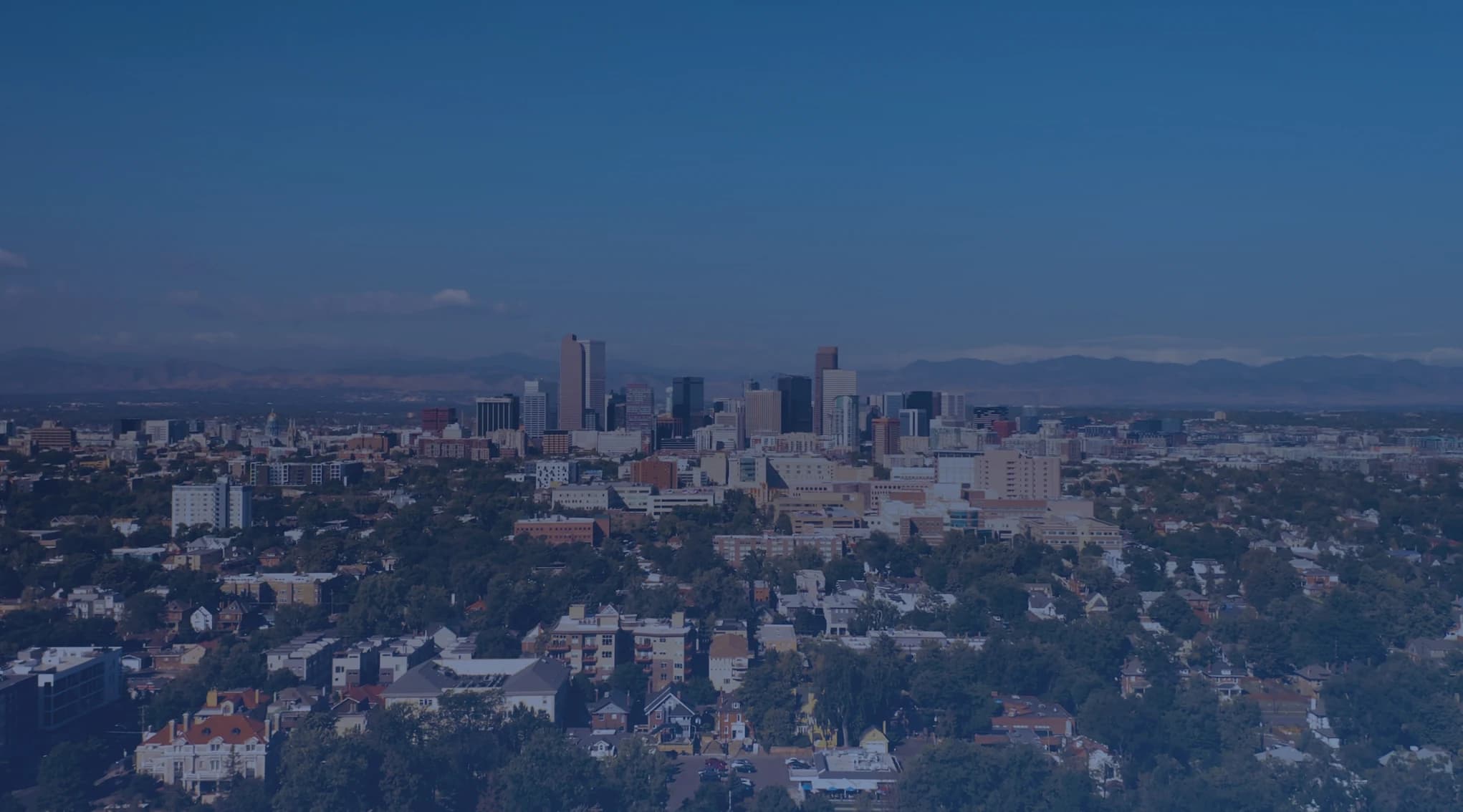 Denver skyline with the snow-capped Rocky Mountains and Front Range foothills rising in the background on a clear Colorado day
