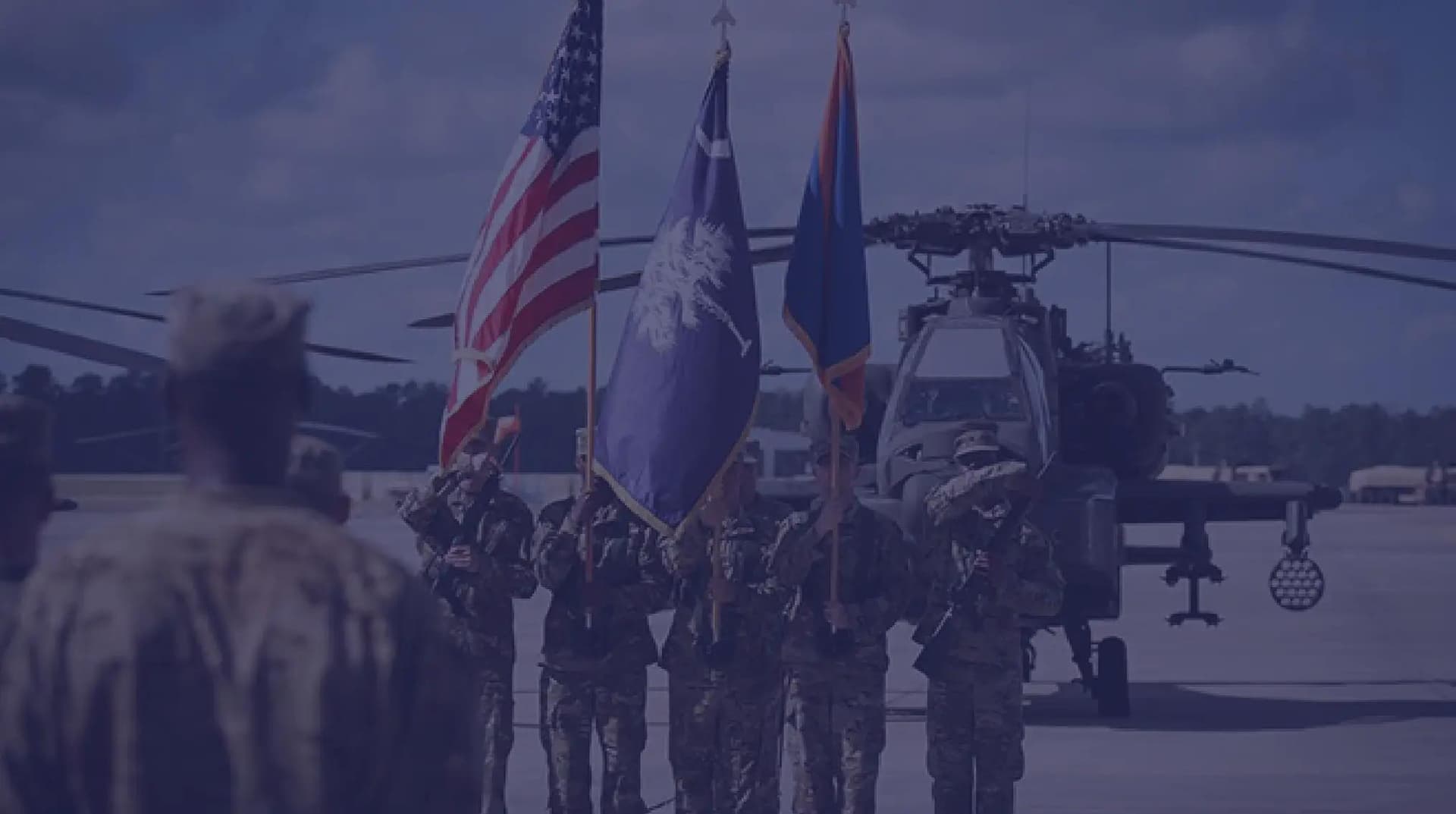 A change of command ceremony in front of AH-64 Apache helicopters.