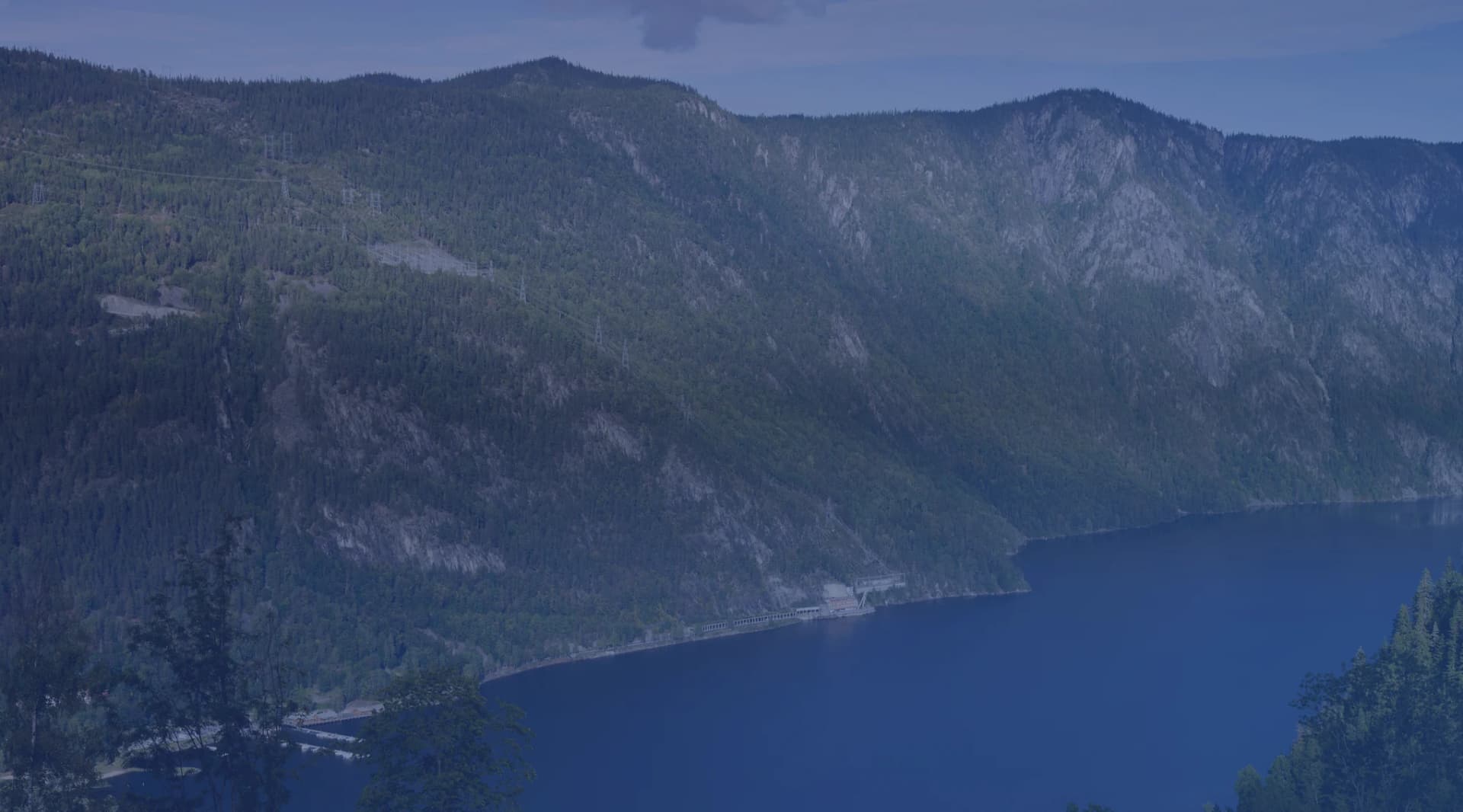 A deep blue lake ringed by green forested mountains, like the lake country of New York North Country near Watertown and Fort Drum.