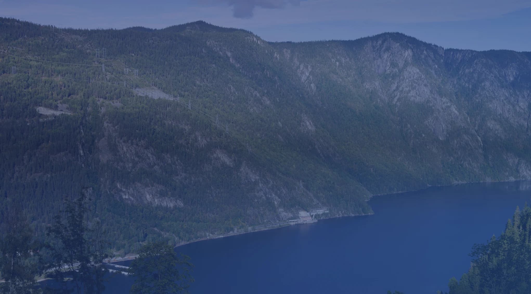 A deep blue lake ringed by green forested mountains, like the lake country of New York North Country near Watertown and Fort Drum.