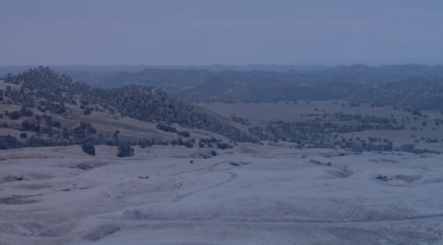 Golden grassland and low rolling hills under a wide open sky, like the prairie country around Lawton and Fort Sill, Oklahoma.