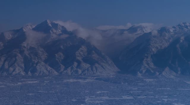 Aerial view of snow-covered Wasatch Mountains rising above the city grid of the Ogden and Salt Lake valley, Utah
