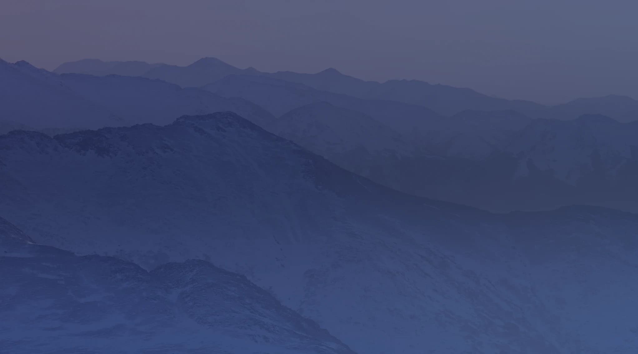 Snow-dusted ridgelines of the Chugach Mountains near Anchorage, Alaska, recede into the distance at sunset