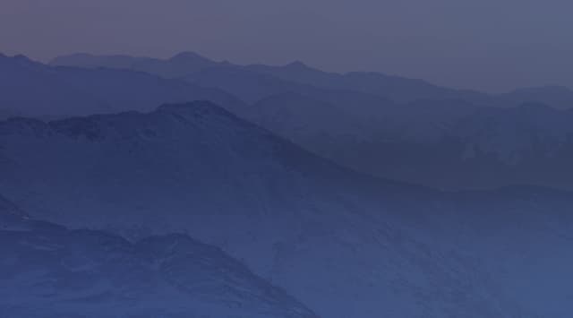 Snow-dusted ridgelines of the Chugach Mountains near Anchorage, Alaska, recede into the distance at sunset