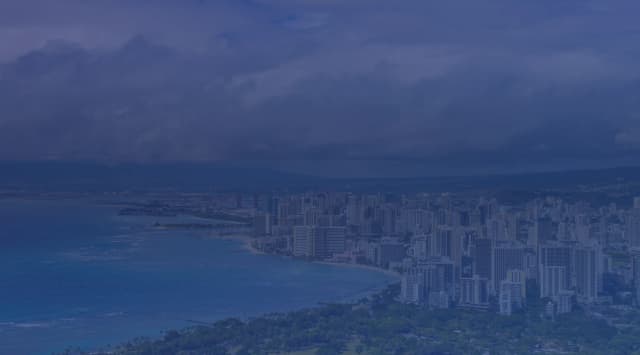 Aerial view of the Honolulu skyline and Waikiki Beach from Diamond Head, with turquoise ocean water and the Koolau Mountains in the background