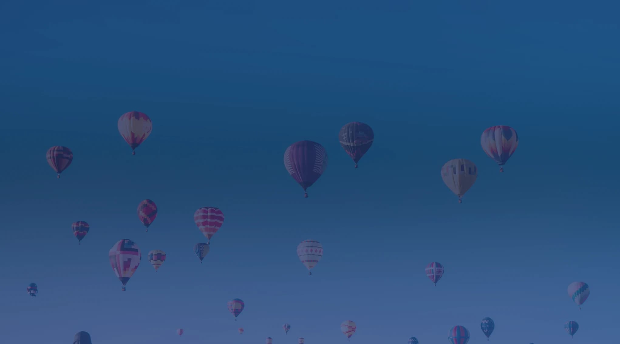 Colorful hot air balloons rising at dawn over the high desert near Albuquerque, New Mexico, with open sky above the Rio Grande valley