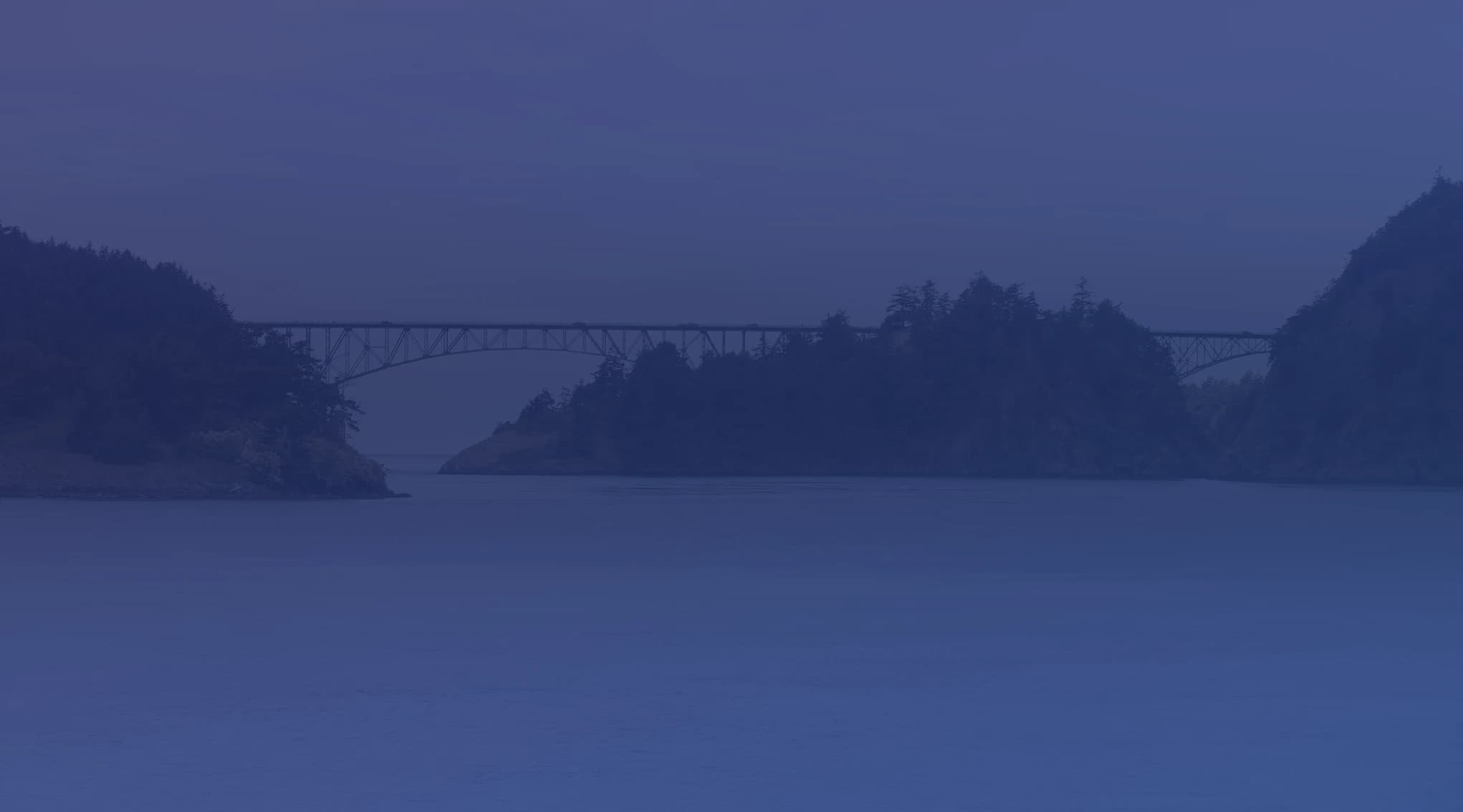 Deception Pass bridge spanning the Salish Sea strait between Whidbey Island and Fidalgo Island, with evergreen forest and blue water below