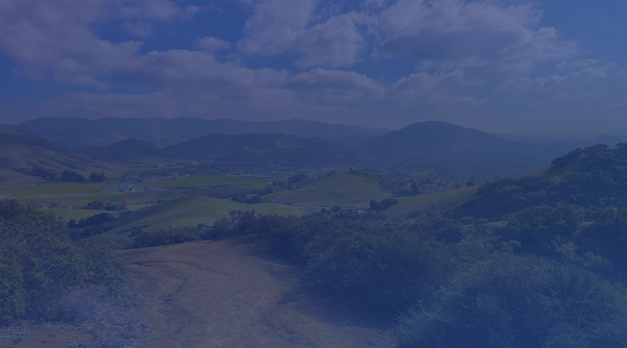 A dirt road winding through rolling green hills on the Central Coast of California, near the Lompoc valley and Vandenberg Space Force Base