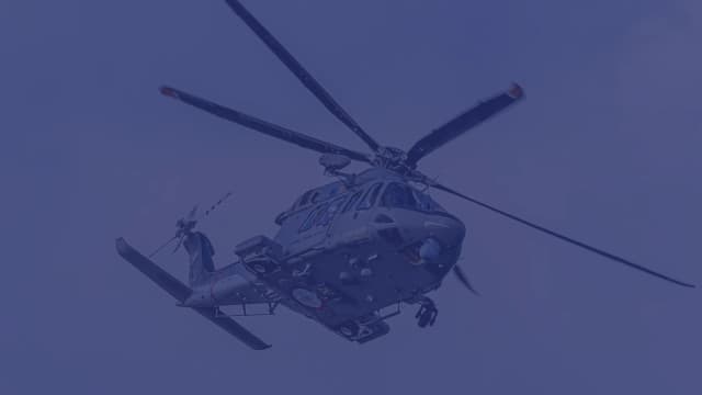 A military helicopter hovering against a deep blue Northwest Florida sky.