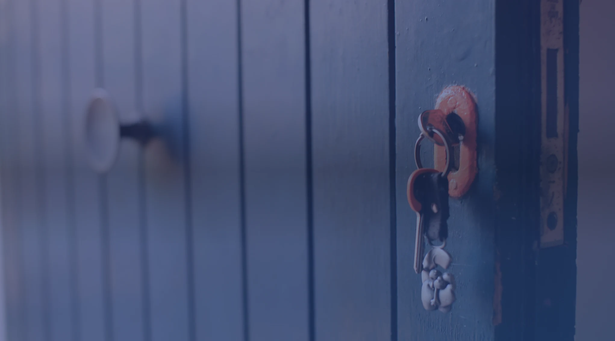 A close-up of a set of house keys hanging in a front door lock