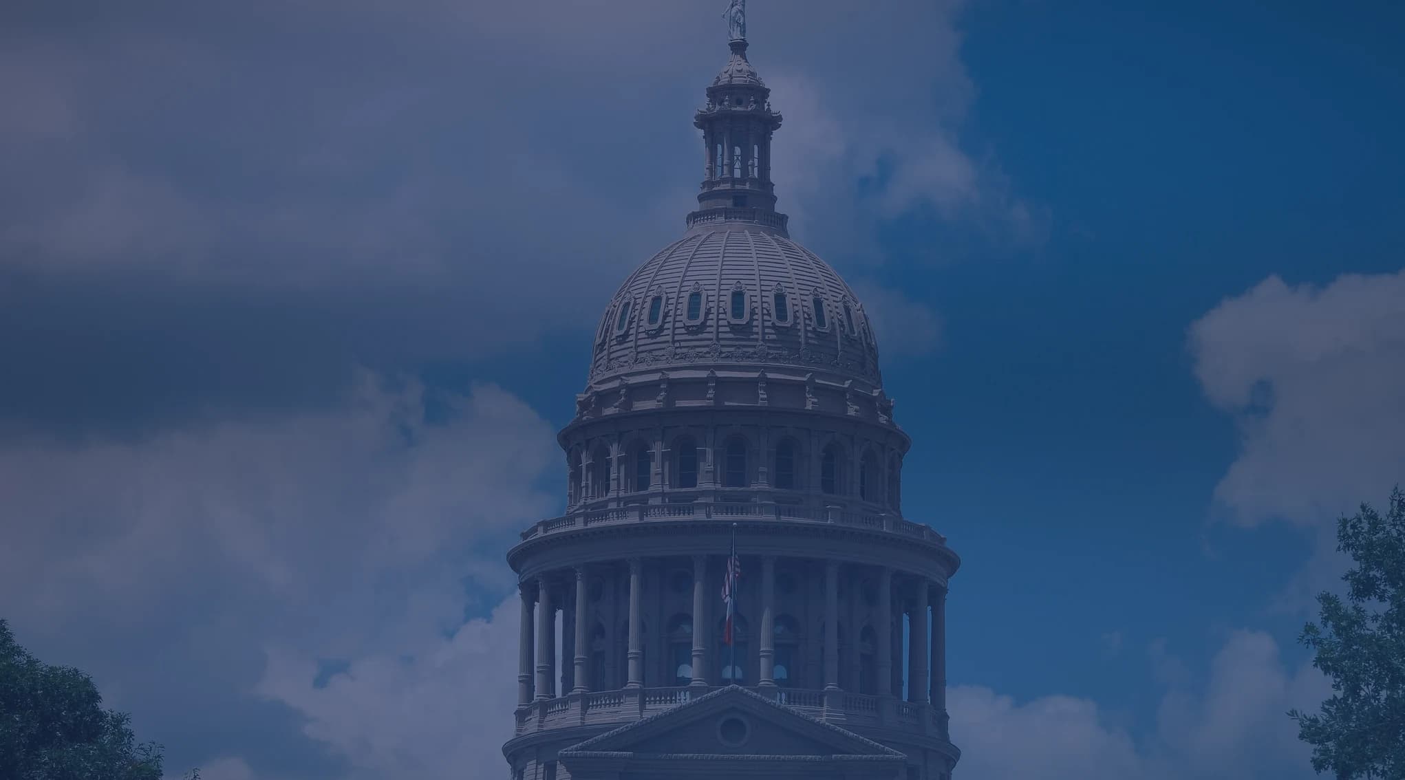 The dome of the Texas State Capitol in Austin against a blue, partly cloudy sky.