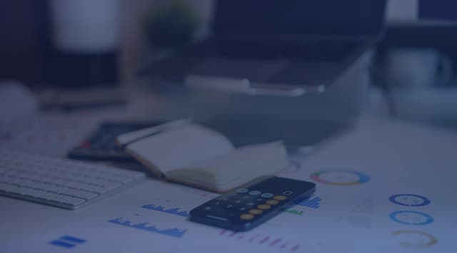 A desk with financial charts and a calculator used for retirement planning