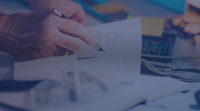 A close-up of hands signing a document at a desk