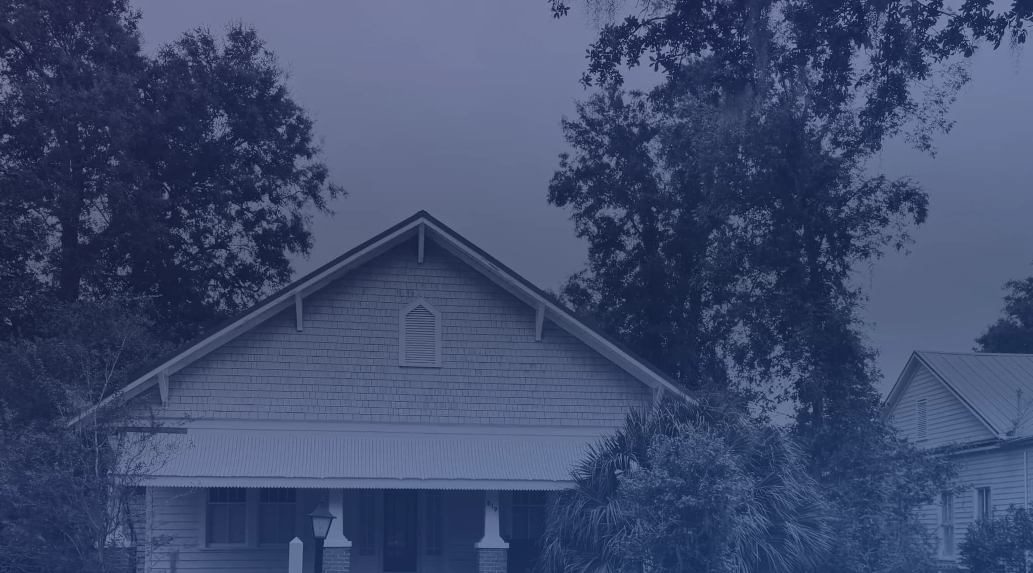 Single-story home with a wide covered porch shaded by trees